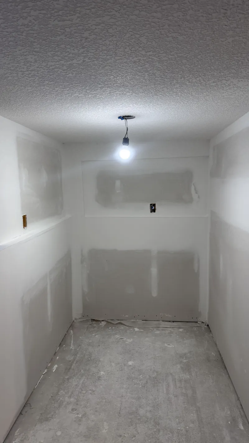 Basement drywall finishing with textured ceiling and mudded walls in Calgary home renovation project.